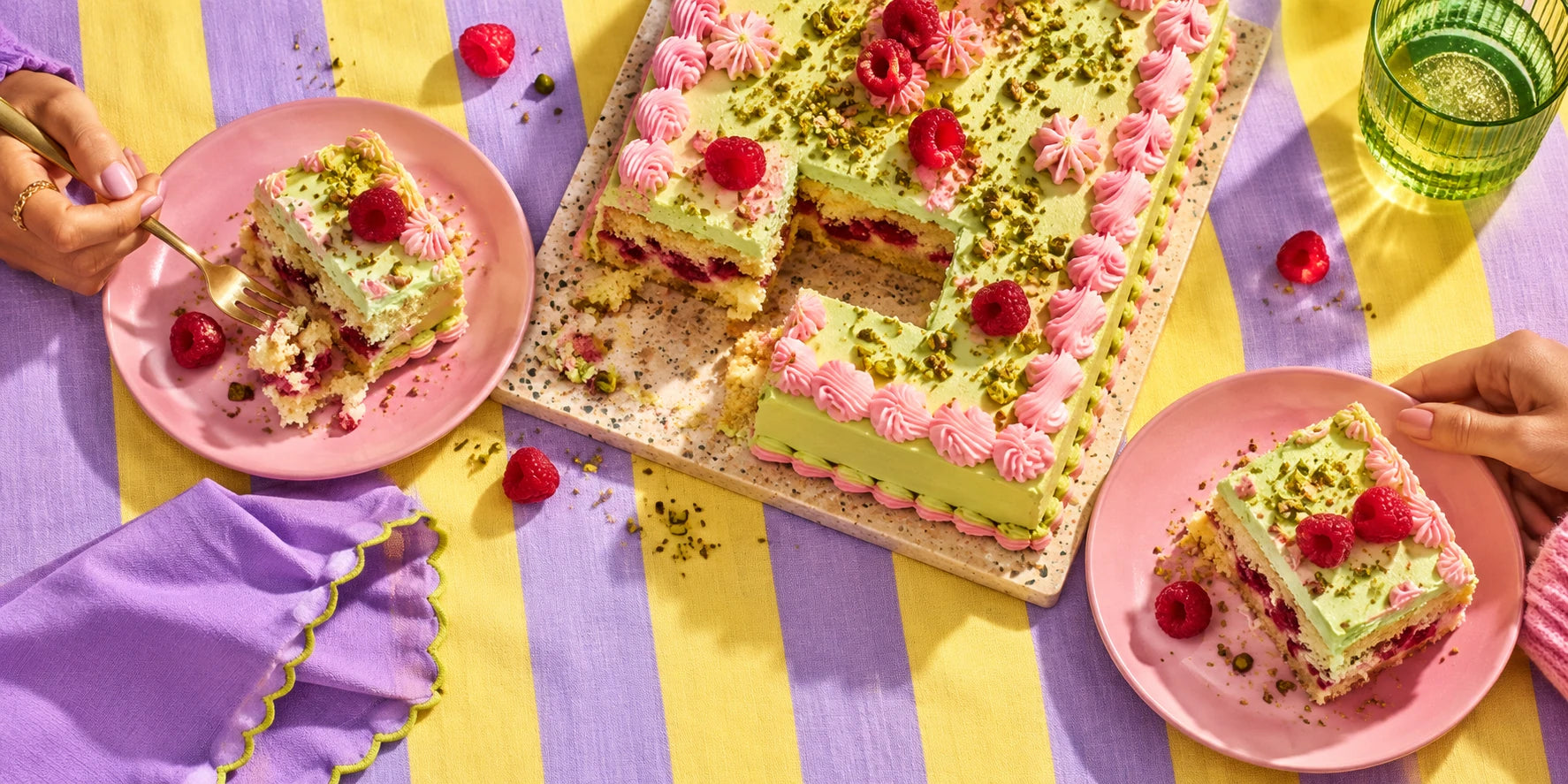 Friends sharing pistachio raspberry cake at a striped table